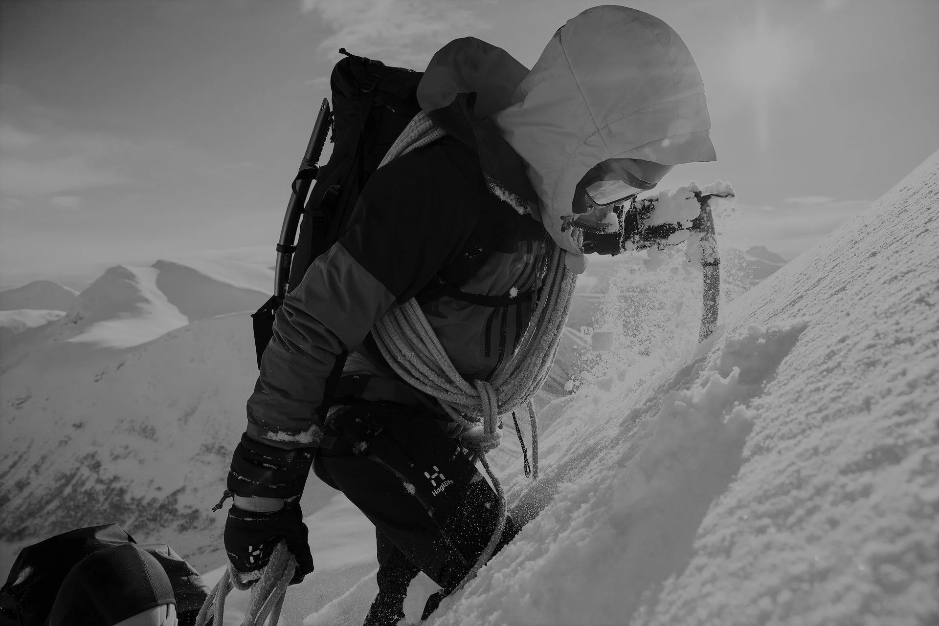 mountaineer with rope and ice axe on top of a snow-covered mountain peak.