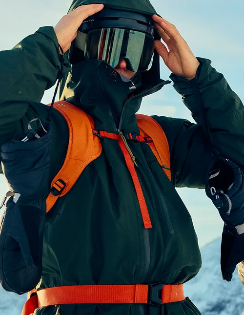 Close-up image of a male skier with helmet, googles ski clothes and backpack