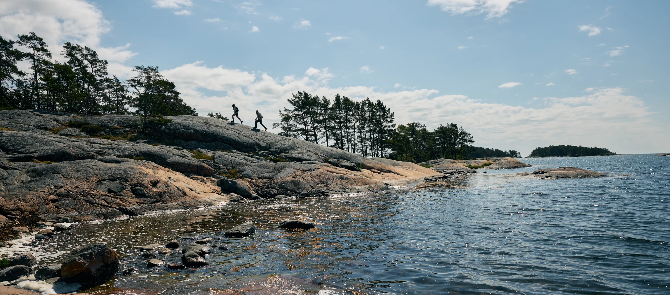 Couple hiking on the rocks in the summer wearing Haglöfs