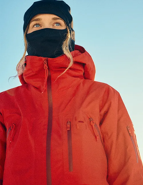 Close-up on skier (women) with balaclava and a read ski jacket 