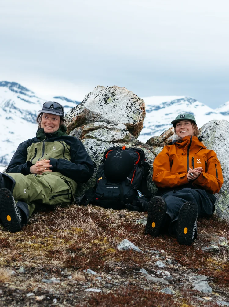 A man and a women sitting on a mountain in Haglöfs outdoor clothes