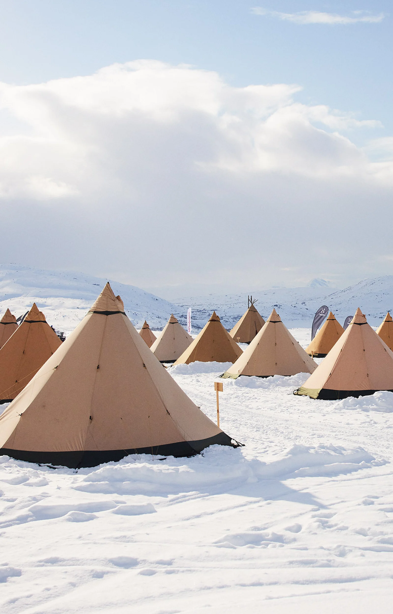 Camp full of tipi tents out in the snow.