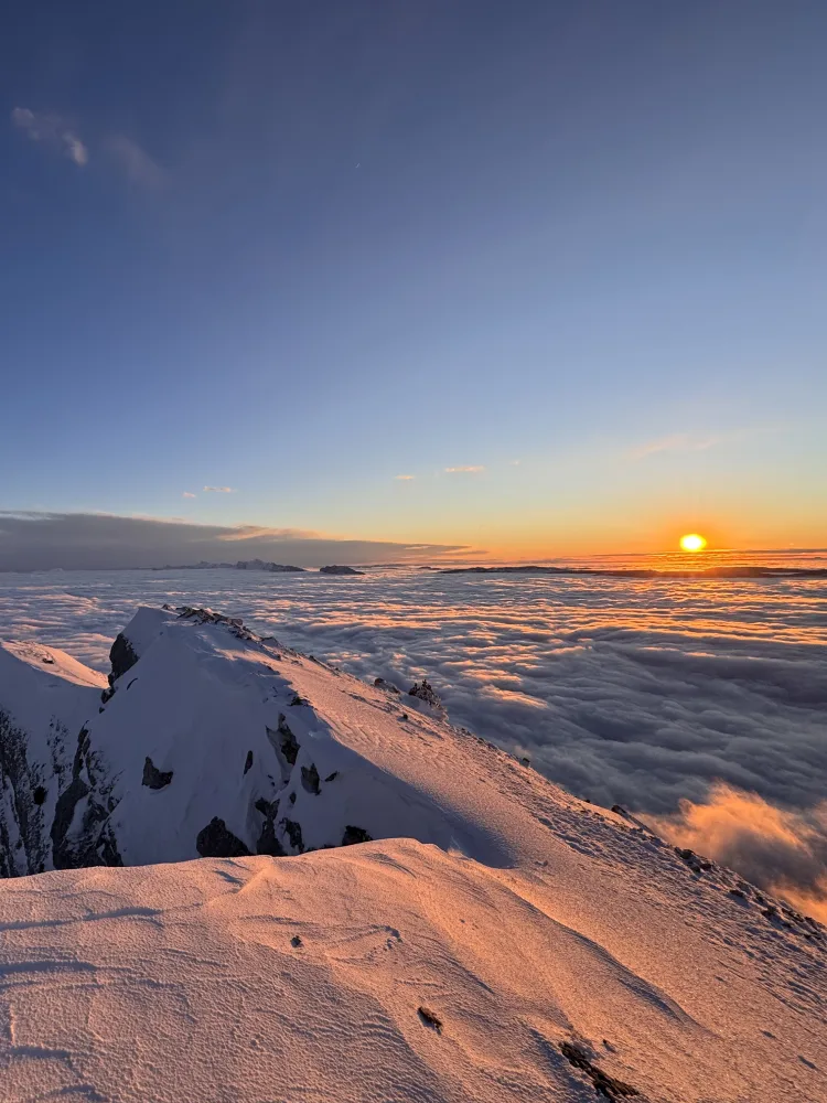 At the top of a snowy mountain in sunset.