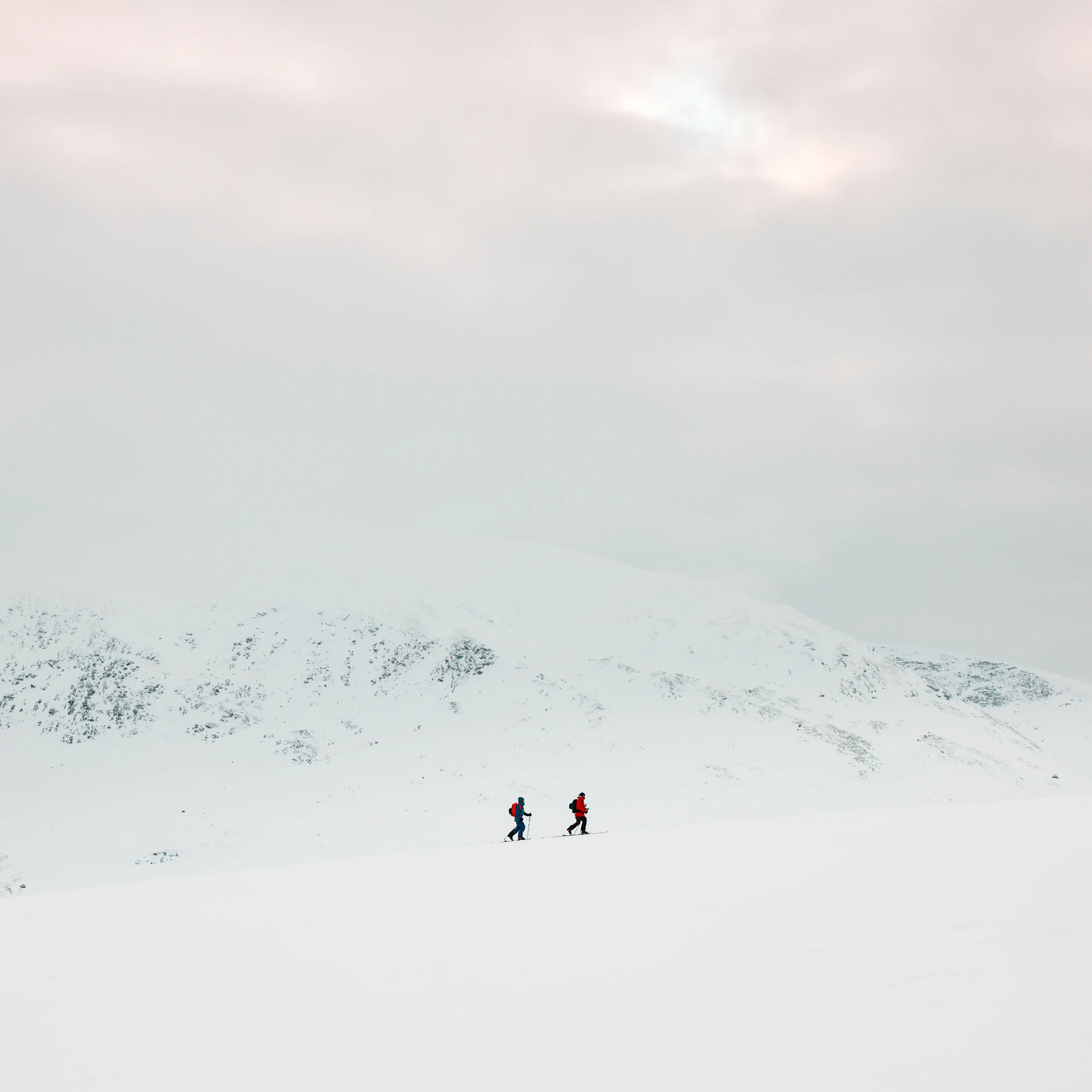 2 guys ski touring in a snowy weater in the mountains