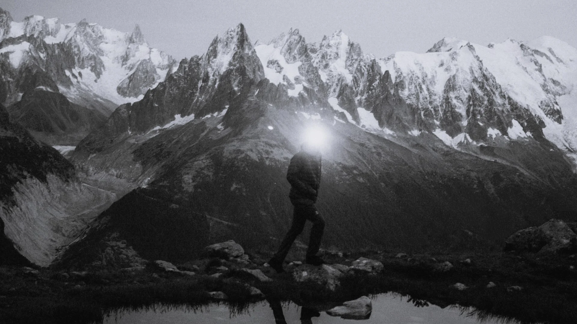 A man hikes at dawn with a headlamp on top of a mountain.