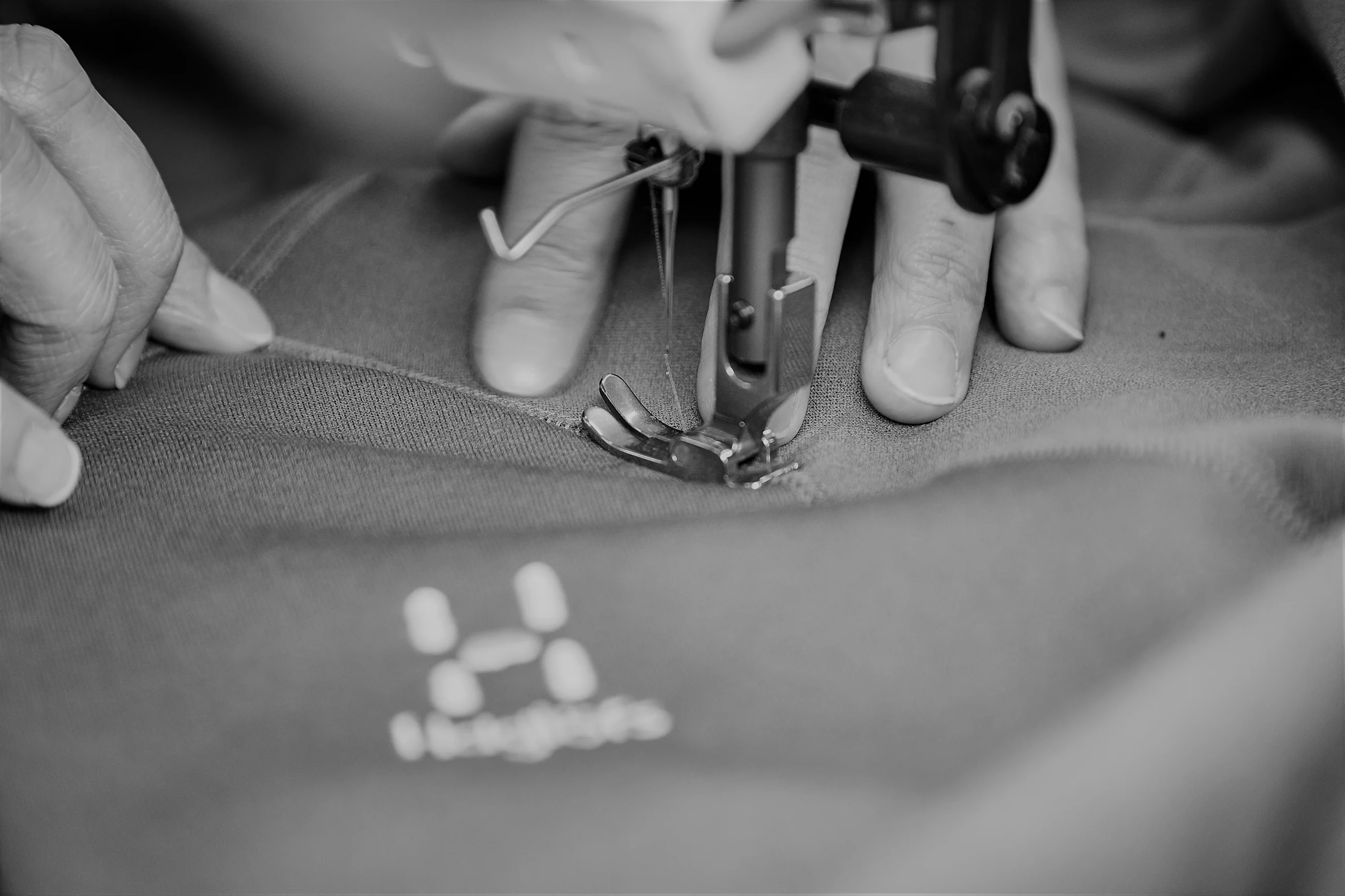 A person sewing a jacket with a sewing machine.