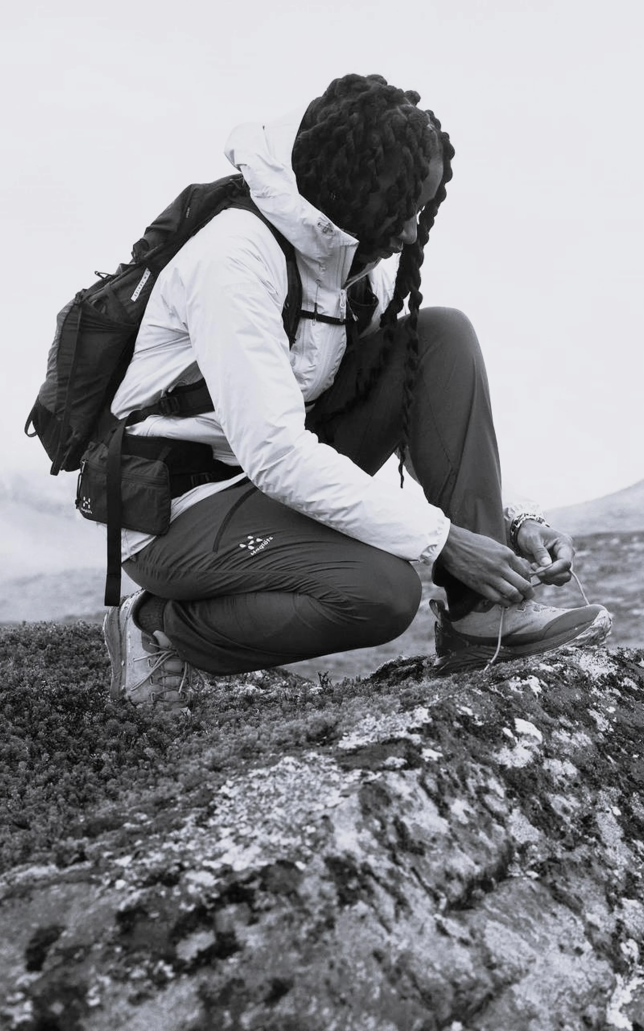 Haglöfs Responsible materials girl on a rock tying her shoe